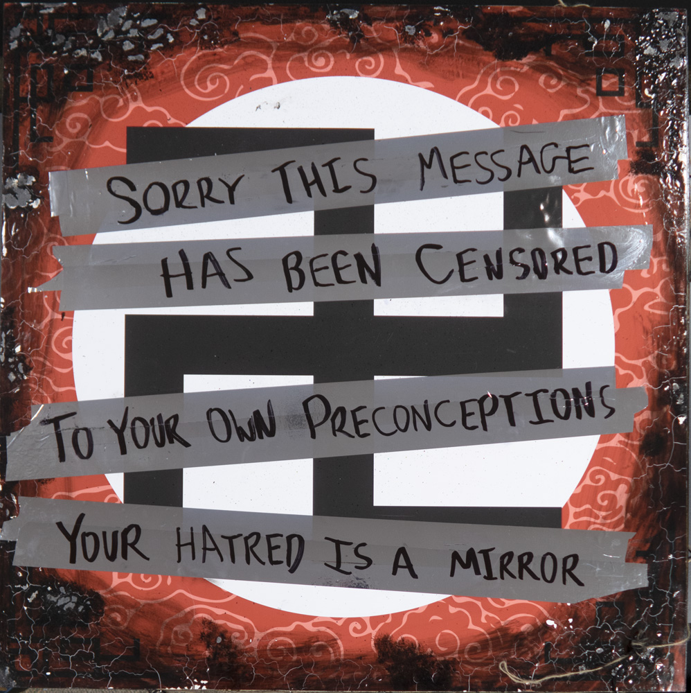 A Manji (swastika) symbol has been covered with metallic tape that says "Sorry this message has been censored to your own preconceptions. Your hatred is a mirror."